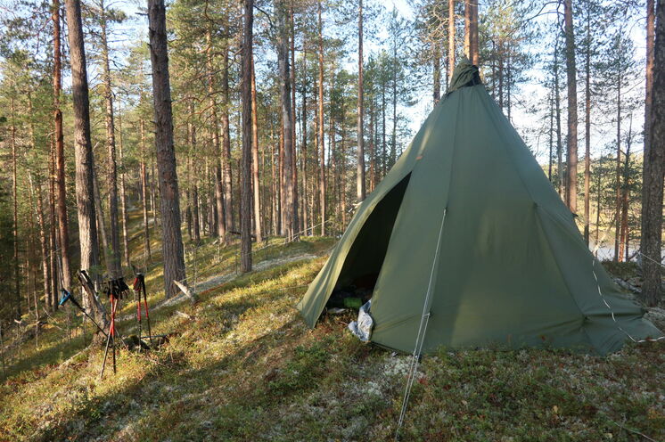 Dieses typisch finnische Tipi ergänzt als Gemeinschafts- und Aufenthaltsraum die niedrigen Schlafzelte.